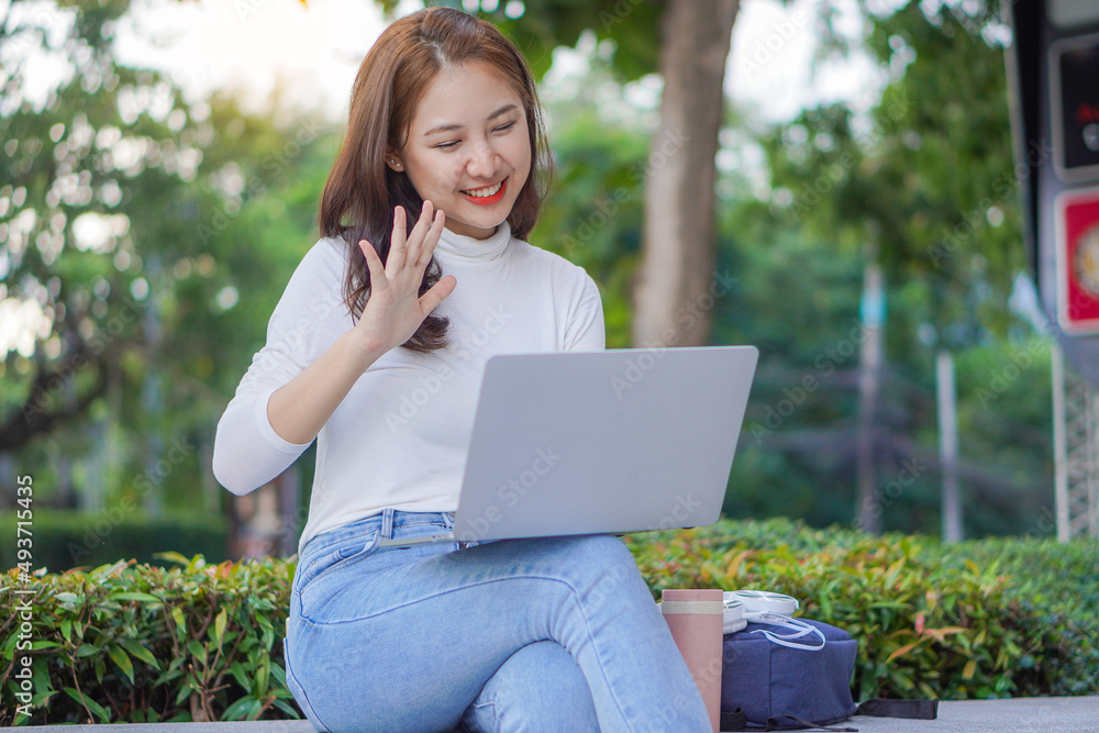 Asian woman publicly uses their laptop to study and work outdoors in shopping malls. Asian woman publicly uses their laptop to study and work outdoors in shopping malls.