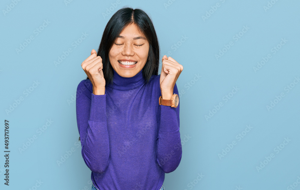 Fototapeta premium Beautiful young asian woman wearing casual clothes excited for success with arms raised and eyes closed celebrating victory smiling. winner concept.
