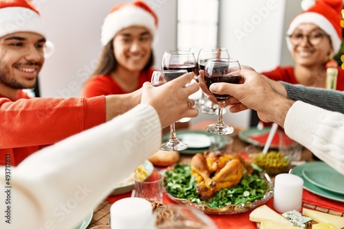 Group of young people smiling happy celebrating christmas toasting with wine at home.