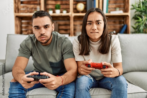 Young latin couple frustrated playing video game at home.