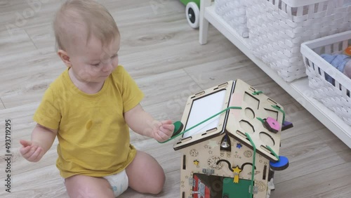 Child having fun playing with wooden busy board, happy kid play with educational learning toy enjoy leisure activity at home. High quality 4k footage photo