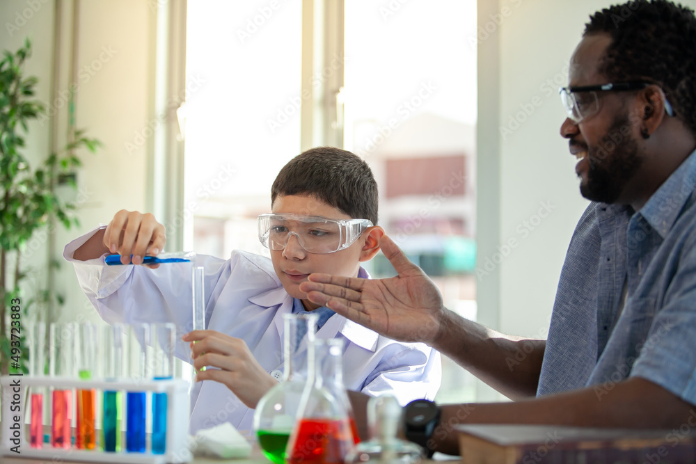 Students mixes chemicals in beakers. enthusiastic teacher explains chemistry to children, chemistry student showing new experiment to teacher science class Students mixes chemicals in beakers. enthusiastic teacher explains chemistry to children, chemistry student showing new experiment to teacher science class