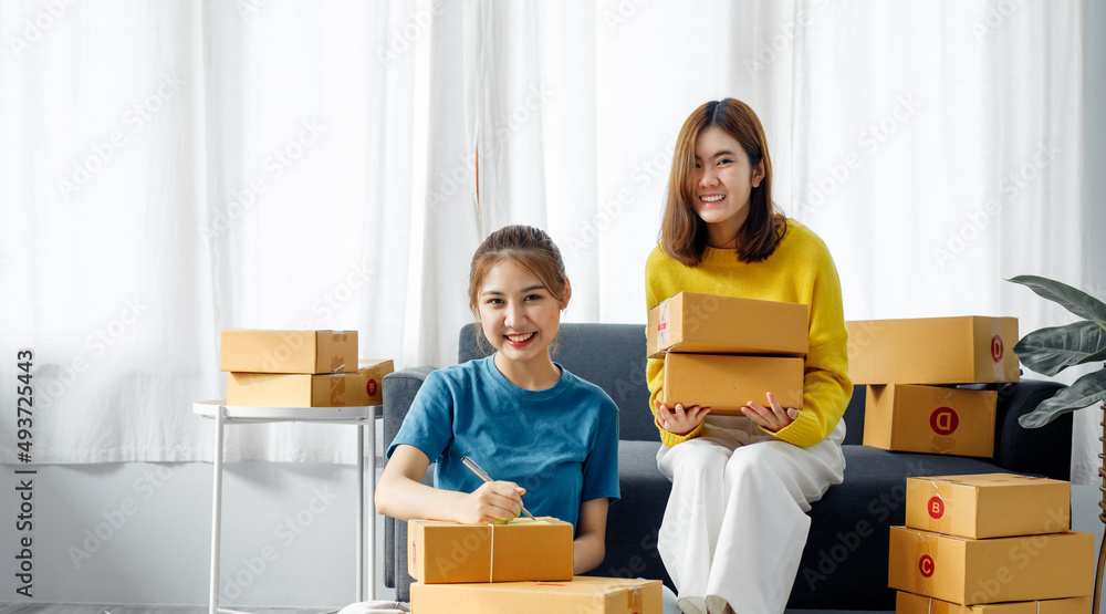 Two Asian Young business woman on sofa at home. startup sme small business entrepreneur SME distribution warehouse with parcel mail box. SME Online marketing and product packaging and delivery service Two Asian Young business woman on sofa at home. startup sme small business entrepreneur SME distribution warehouse with parcel mail box. SME Online marketing and product packaging and delivery service