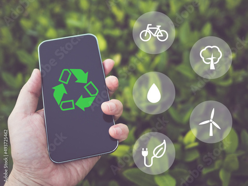 Hand holding smartphone with recycling eco-friendly application icons, save the earth environment concept, ecology technology, go green