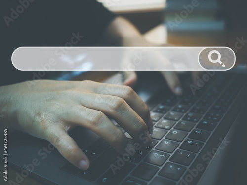 Hands typing on keyboard laptop with search bar icon on screen, search engine optimization concept, SEO marketing, searching data information on internet