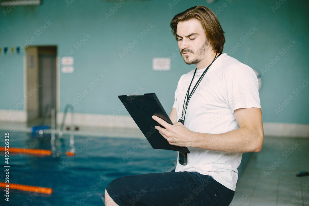 Serious trainer holding clipboard and blowing whistle Serious trainer holding clipboard and blowing whistle