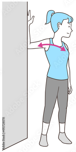 壁を使って大胸筋のストレッチをする女性、シンプルな色