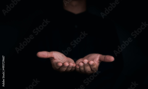 Give two hands with nothing on both on dark background with copy space. Close-up receiving gesture of outstretched cupped empty open hands. Concept of giving, donation, receiving, asking, and bribery.