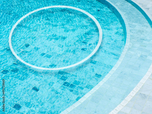 A round shape of a white line makes a decorated circle frame on the swimming pool background. Empty blank space border frame for summer, vacation time, holiday concept.