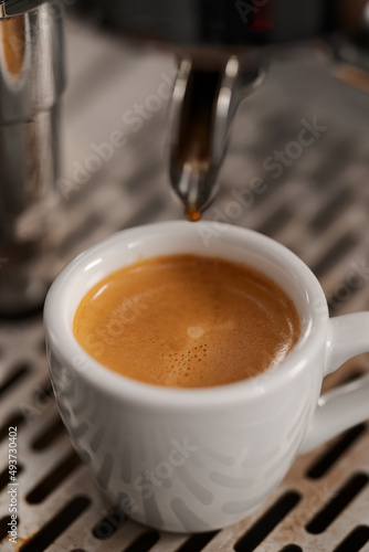 White cup with espresso on coffee machine tray