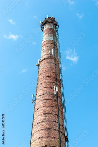 Old brick factory pipe against blue sky.