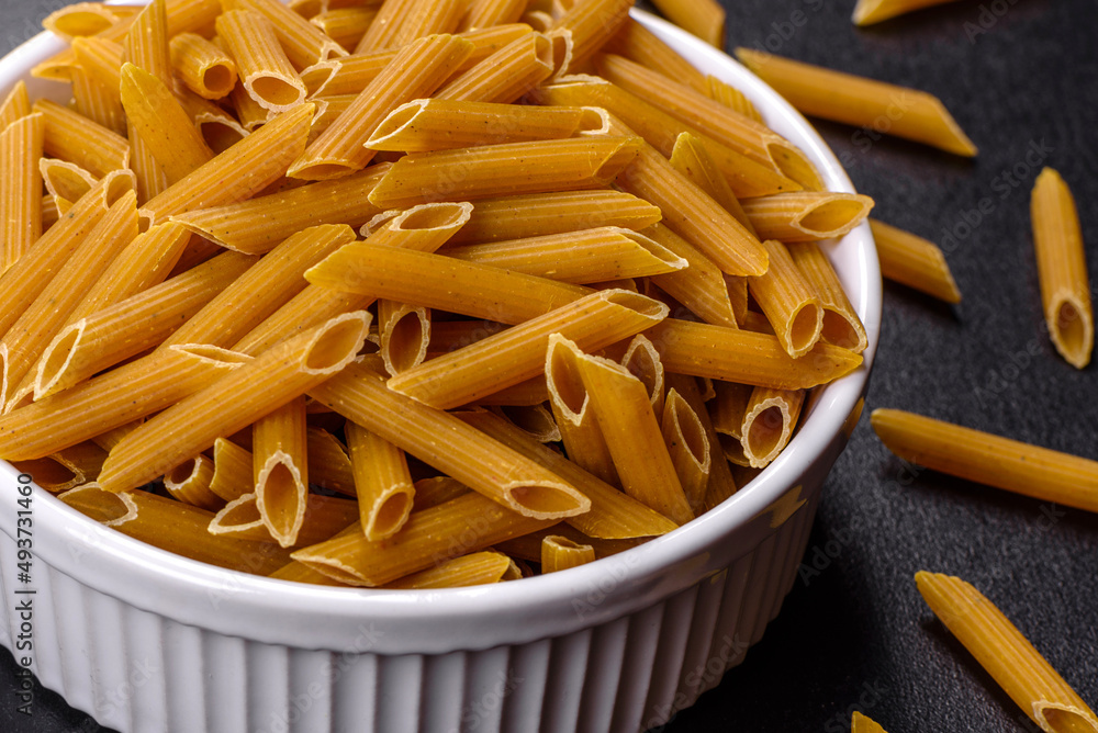 Detail of macaroni pasta useful as a background, texture. Dry pasta. Top view on black background