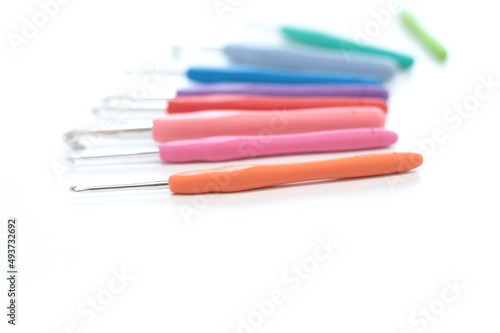 Blurred colorful crochet hooks in different sizes for knitting isolated on white background