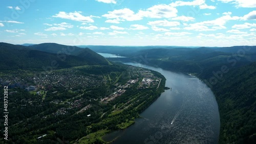 Flying drone along wide river and mountains, hydroelectric power plant in background. Height of bird's flight. Aerial view of beautiful drone shot of Divnogorsk city near Yenisei river.