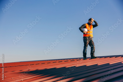 A construction worker standing on the roof and having hard times on work.