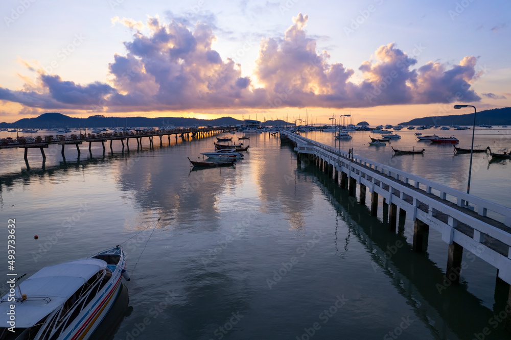 Fototapeta premium Aerial View Top down Drone shot of Yacht and sailboat parking in marina at Chalong bay Transportation and travel background concept.Beautiful sea with mountain sunrise sky clouds sunset background