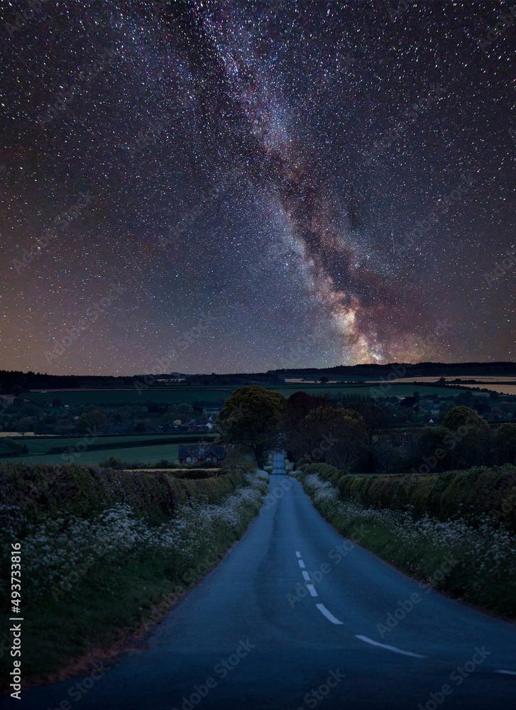 Vibrant Milky Way composite image over landscape of empty road in English countryside