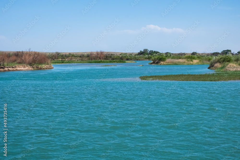 Ili river in spring time. Beautiful river with blue water and sky. Wild nature landscape background.