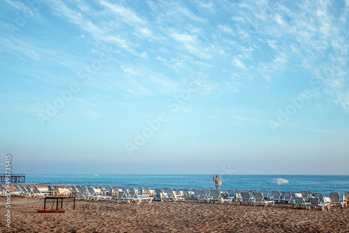 Beach resort, white deck chairs by the sea with sand over the sea. Concept of summer holidays, holidays and tourism, holidays. Inspirational holiday banner, copy space. © Aliaksandr Marko