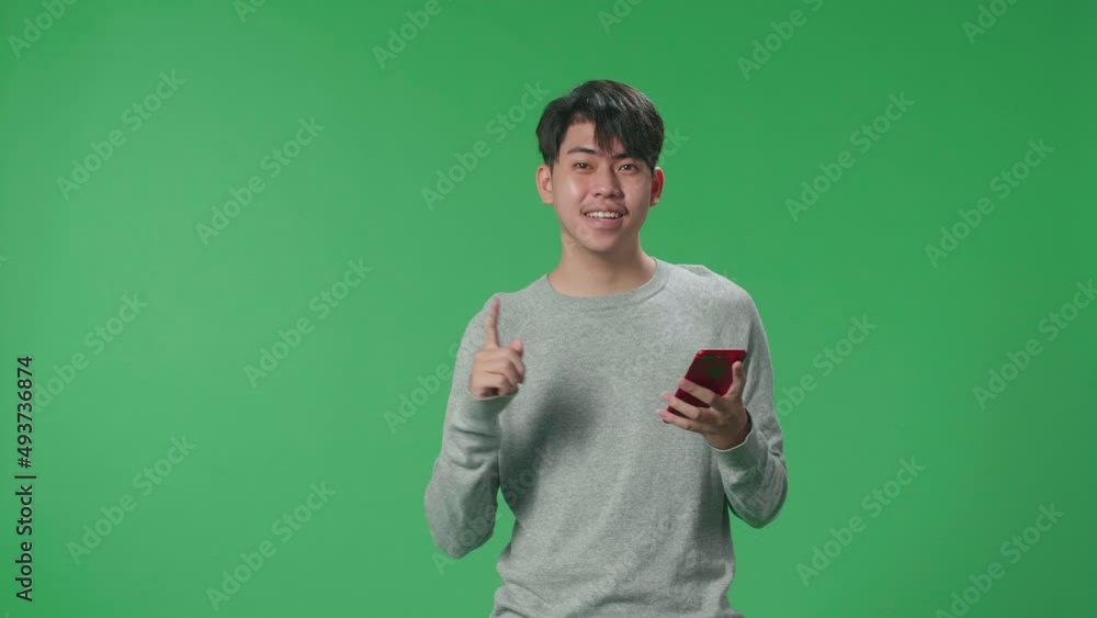An Asian Man Flipping Through The Mobile Phone With A Smile Pointing To The Side While Standing In The Green Screen
An Asian Man Flipping Through The Mobile Phone With A Smile Pointing To The Side While Standing In The Green Screen