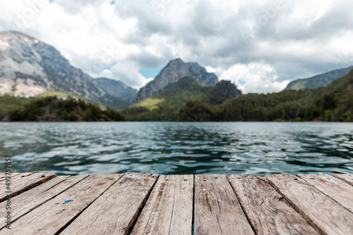 Boards background with landscape of mountains and lake for your decoration. Beautiful nature, white clouds, template table.