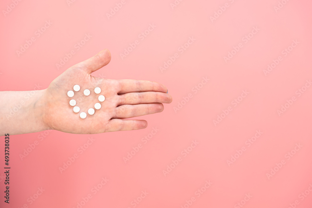 Pills in the shape of a heart on a female palm, pink background. Pills in the shape of a heart on a female palm, pink background.