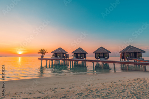 Maldives island sunset. Water bungalows resort at islands beach. Indian Ocean, Maldives. Beautiful sunset landscape, luxury resort villas and colorful sky. Summer vacation holiday and travel concept
