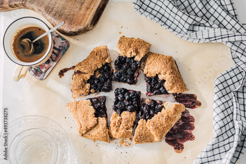 Blueberries Galette, a free-form pie with crust folded partway over the top of the filling. Traditional French fruit tart. Easy recipe, home backing from scratch. Food flat lay. photo