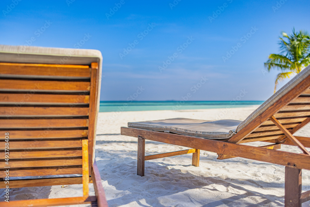 Fototapeta premium Beautiful beach. Couple chairs on the sandy beach near the sea, blurred island landscape exotic shore coast. Summer holiday and dream vacation concept for tourism. Inspirational tropical resort hotel.