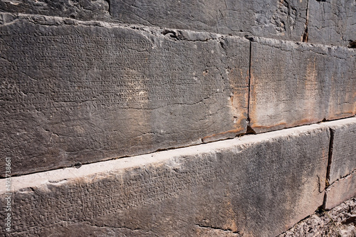 Ancient greek text on a block wall in the ruins of Delphi