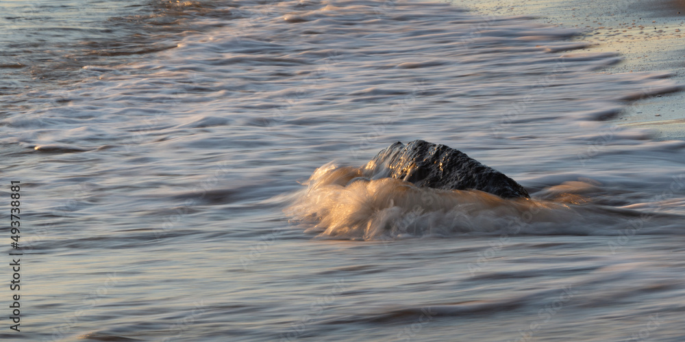 Obraz premium Ocean waves crashing on the rocks at beach at sunrise
