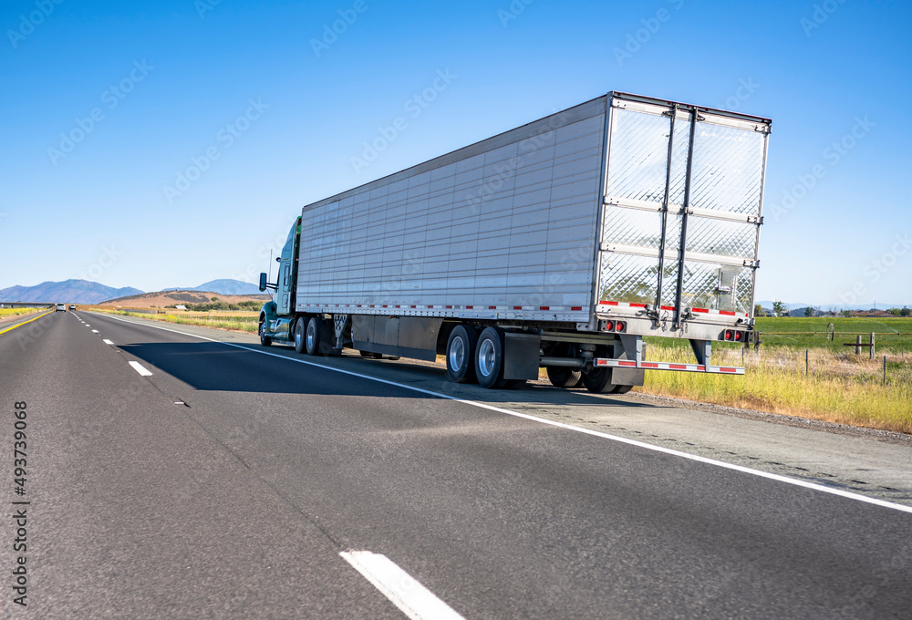 Green big rig semi truck with cargo in refrigerator semi trailer standing out of service on the road shoulder in Washington Green big rig semi truck with cargo in refrigerator semi trailer standing out of service on the road shoulder in Washington