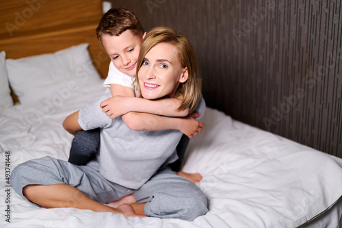 Playful mother and son lying in bed together