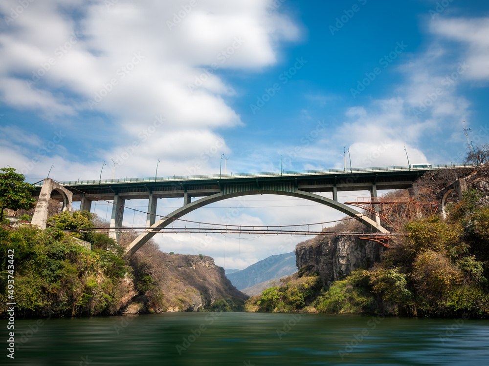 A high Bridge over Grijalva river at the Sumidero Canyon, a natural deep canyon in Chiapas, Yucatan, Mexico. View from the water on a boat tour of the Canyon, a popular attraction in Southern Mexico.