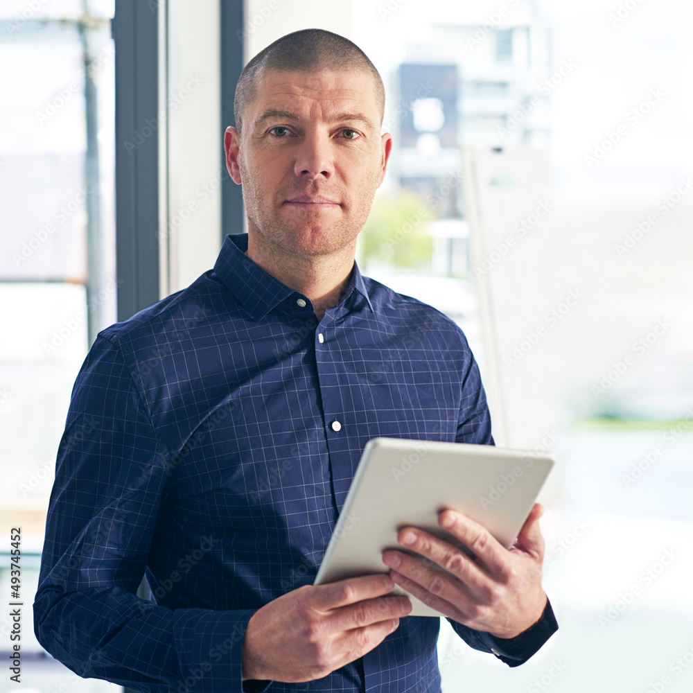 With wireless technology Im always online and up to date. Portrait of a businessman using a digital tablet in a modern office. With wireless technology Im always online and up to date. Portrait of a businessman using a digital tablet in a modern office.