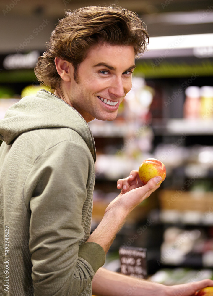 Fototapeta premium I want this one. A young man at the store buying fruit.