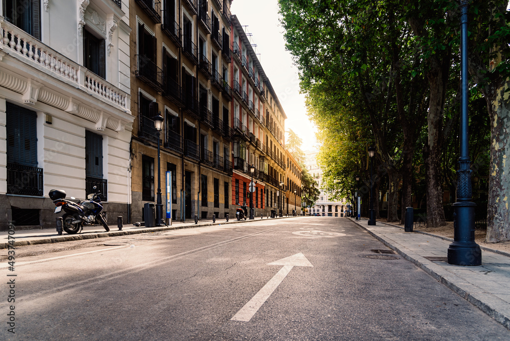 Street in central Madrid at early morning with sunflare on background. Calle San Quintin