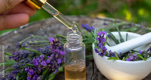 Herbal oil and lavender flowers on a wooden background. Nature.