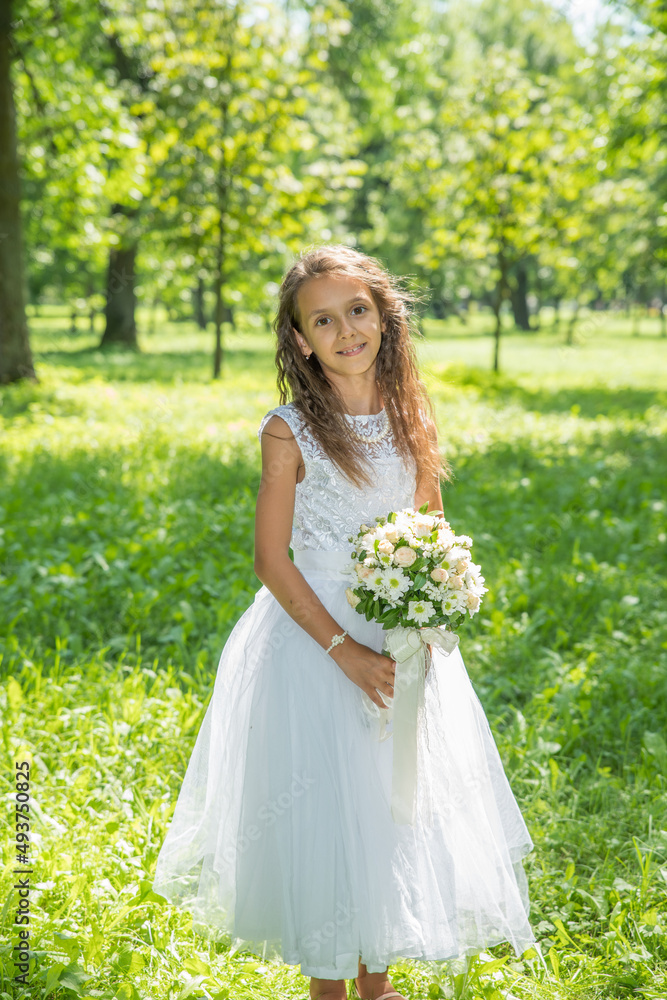 Little girl in a white dress with a bouquet of flowers in a summer park. Little girl in a white dress with a bouquet of flowers in a summer park.