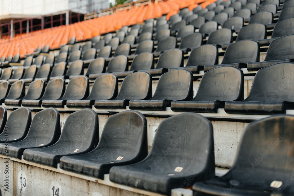 Fototapeta premium Empty stands and seats for fans and fans in the open-air stadium. Lack of fans during the pandemic.