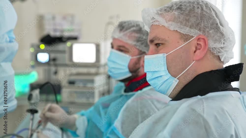 Male surgeons look intently on the screen. Doctor uses modern equipment at operation. Blurred backdrop. Male surgeons look intently on the screen. Doctor uses modern equipment at operation. Blurred backdrop.