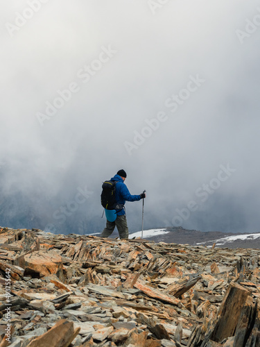 Solo climbing. Activities man climb to the top of a misty stone hill. People in difficult conditions. Foggy day in the mountains. Difficult climb to the top of the mountain.