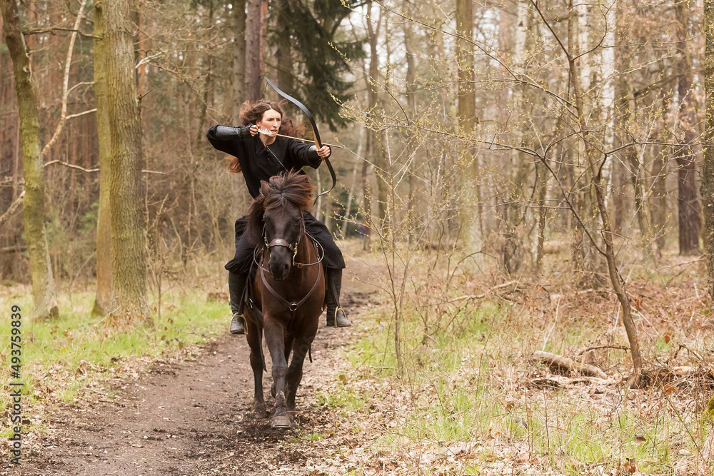 beautiful black dressed woman in historical costume just shooting an arrow from a bow beautiful black dressed woman in historical costume just shooting an arrow from a bow