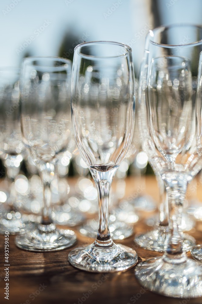 Row of empty champagne glasses on a table outdoors with sun reflection. Selective focus. Celebration concept Row of empty champagne glasses on a table outdoors with sun reflection. Selective focus. Celebration concept