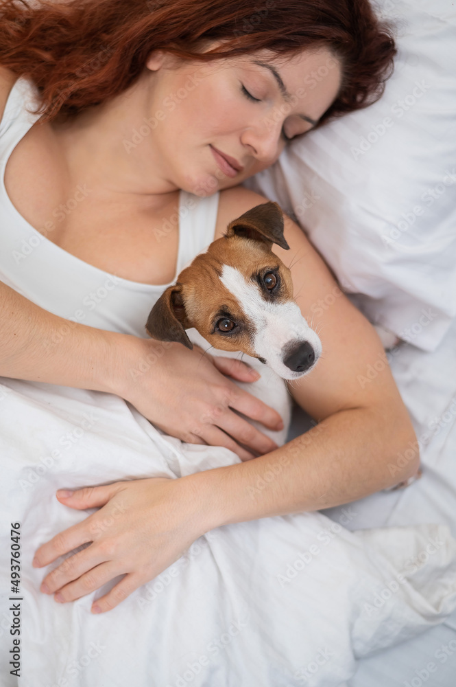 Caucasian woman is napping in bed hugging her beloved dog. Caucasian woman is napping in bed hugging her beloved dog.
