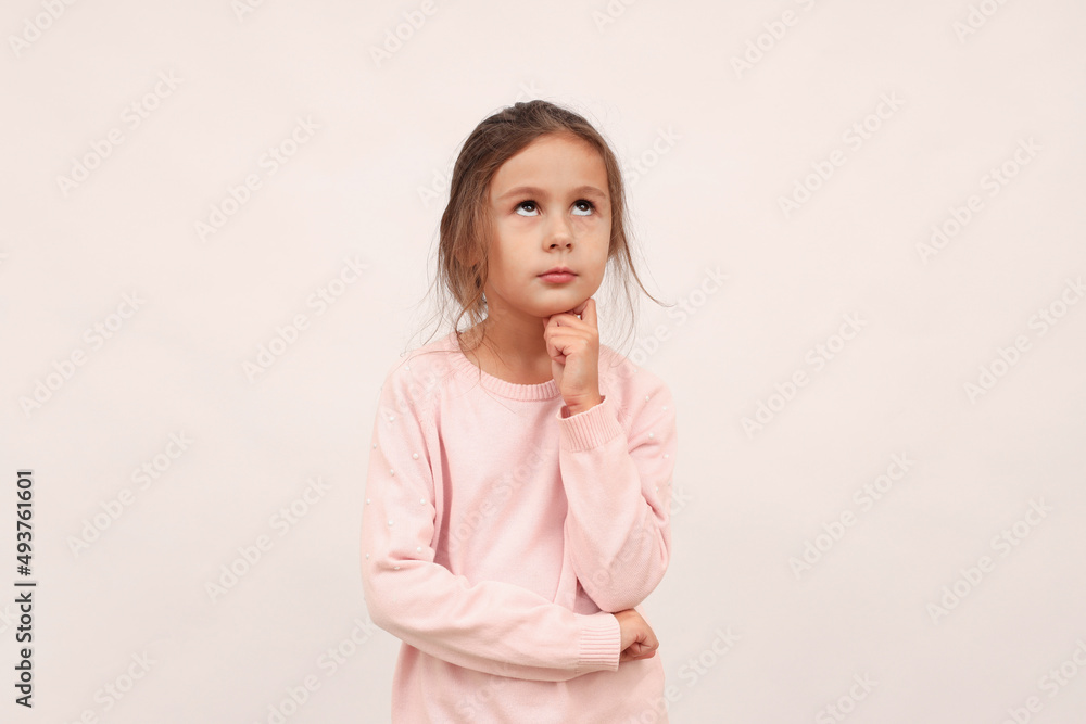 A little thoughtful girl looking up, confused by some idea, will try to find a solution A little thoughtful girl looking up, confused by some idea, will try to find a solution