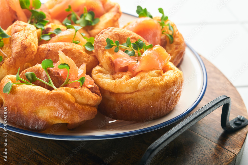 Yorkshire pudding. Traditional English Yorkshire pudding with salmon and radish microgreens side dish on white plate and light grey background table. Top view. Yorkshire pudding. Traditional English Yorkshire pudding with salmon and radish microgreens side dish on white plate and light grey background table. Top view.