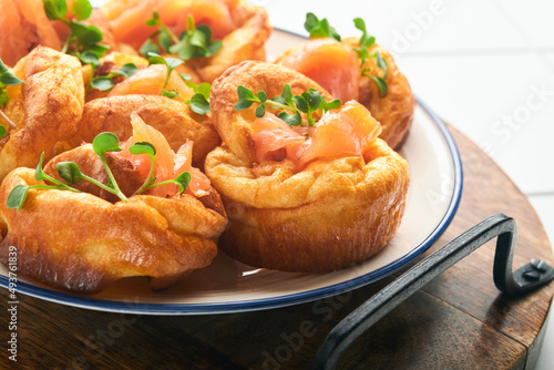 Yorkshire pudding. Traditional English Yorkshire pudding with salmon and radish microgreens side dish on white plate and light grey background table. Top view.