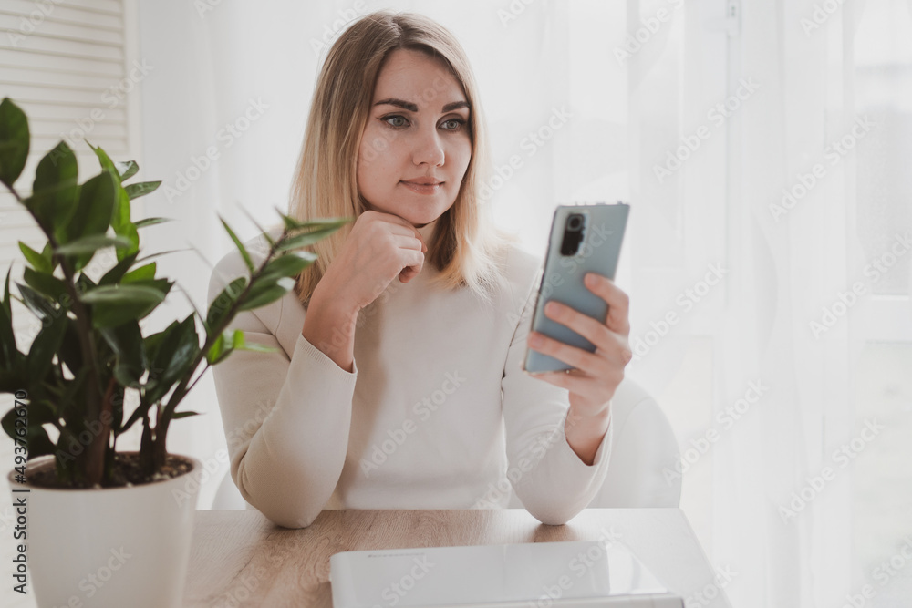 joyful charming woman using laptop and mobile phone smiling while sitting at the workplace joyful charming woman using laptop and mobile phone smiling while sitting at the workplace