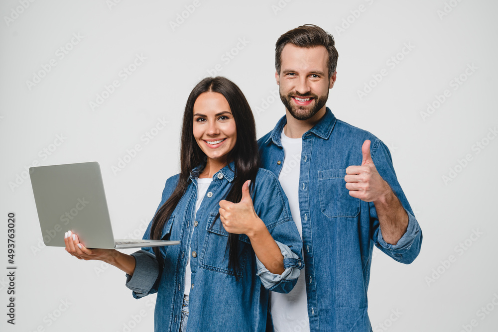 Caucasian young couple spouses friends man and woman holding laptop for e-learning, e-commerce, distant work, watching webinars, showing thumb up isolated in white background Caucasian young couple spouses friends man and woman holding laptop for e-learning, e-commerce, distant work, watching webinars, showing thumb up isolated in white background